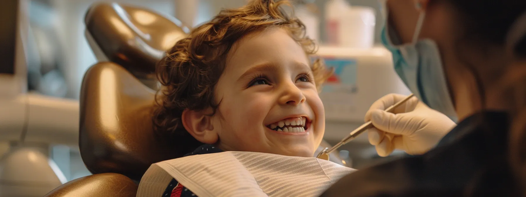 a child sitting in a dental chair, smiling with a dentist preparing to examine their teeth.